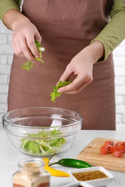 Женские руки добавляют листья салата — стоковое фото