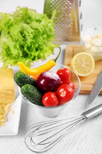 Ustensiles de cuisine et ingrédients pour salade sur table, sur fond clair — Photo