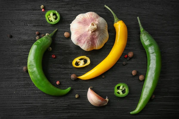 Peperoncini di aglio, verde e giallo su fondo di legno scuro — Foto Stock