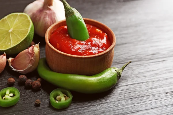 Salsa piccante fatta in casa e spezie su sfondo di legno scuro — Foto Stock