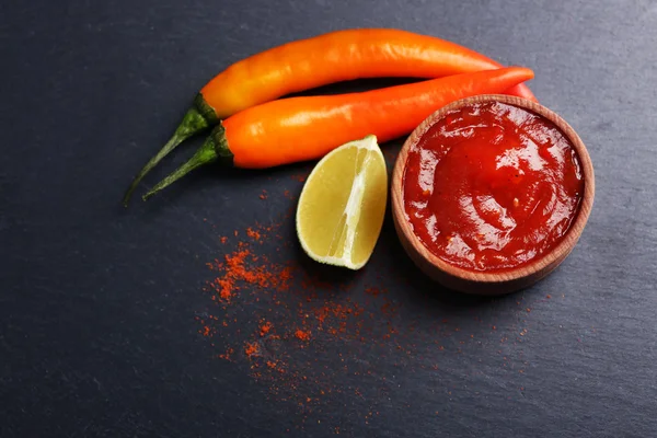 Salsa picante casera y especias sobre fondo oscuro — Foto de Stock