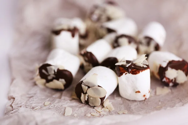 Marshmallows saborosos com chocolate no papel, close-up — Fotografia de Stock