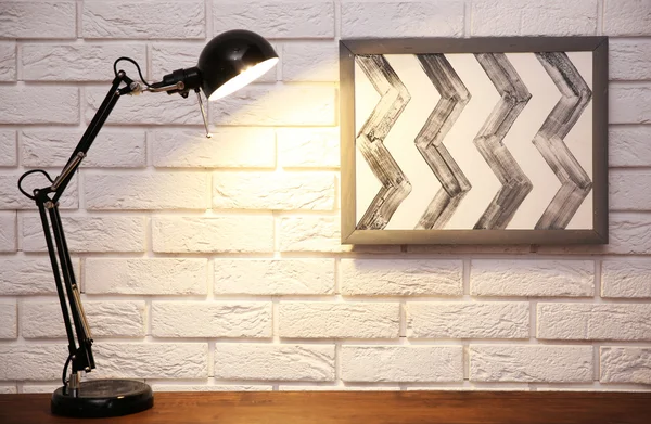 Lampă modernă pe masă pe fundal de perete din cărămidă — Fotografie, imagine de stoc