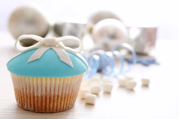 Leckerer Cupcake mit Schleife, Kaffeetasse und Weihnachtsspielzeug auf farbigem Holzhintergrund — Stockfoto