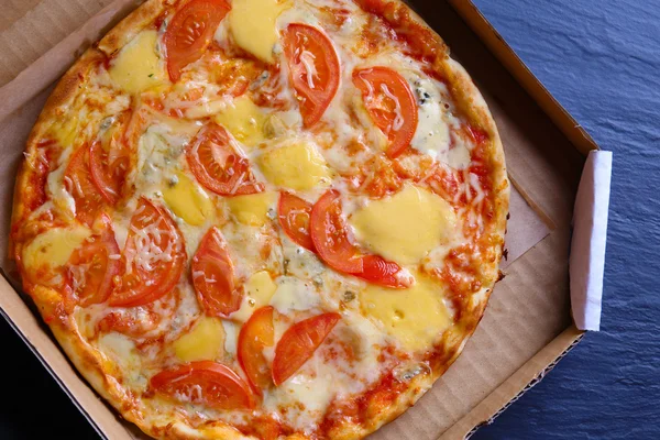 Delicious full of cheese pizza with tomatoes in a carton, close up — Stock Photo, Image