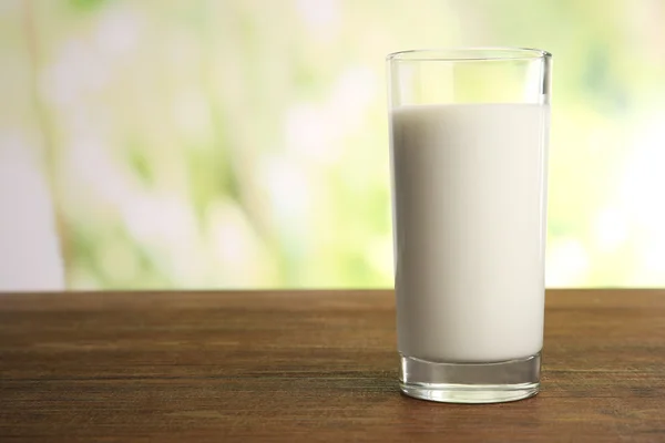 Glass of milk on table on blurred natural background — Stock Photo, Image