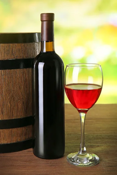 Red wine in glass and in bottle on blurred natural background — Stock Photo, Image