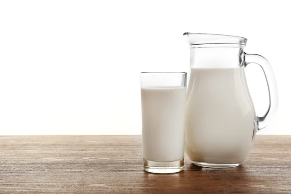 Leche en vaso y en frasco sobre mesa aislada sobre fondo blanco — Foto de Stock