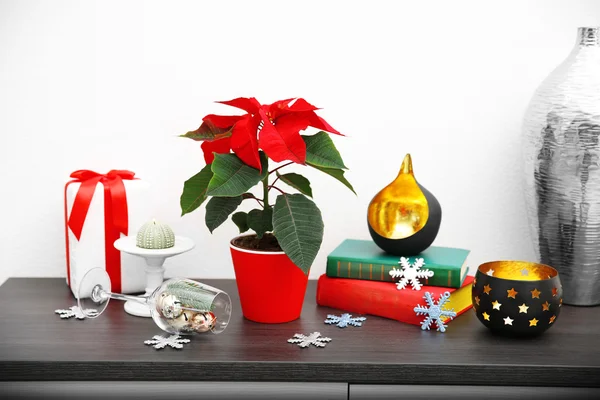 Fiore di Natale poinsettia e decorazioni su scaffale con decorazioni natalizie, su sfondo chiaro — Foto Stock