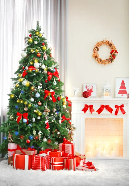 Árbol de Navidad con regalos cerca de la chimenea en una habitación — Foto de Stock