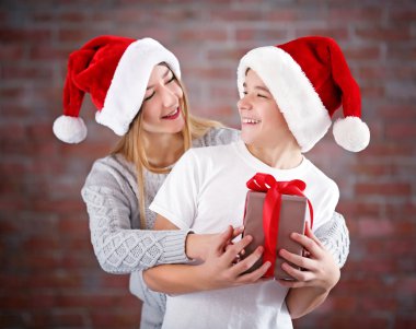 Mutlu kız ve erkek kardeş ile tuğla duvar arka plan üzerinde hediye kutusu