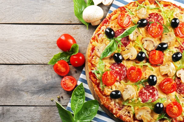 Deliciosa pizza saborosa com ingredientes na mesa de madeira — Fotografia de Stock