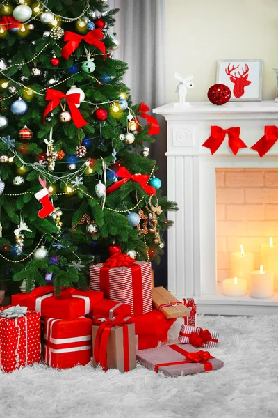 Рождественская елка с подарками возле камина в комнате — стоковое фото