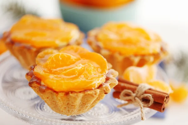 Sweet cakes with tangerines on plate, close up — Stock Photo, Image