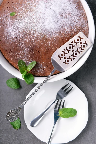 Čokoládový koláč s cukrem prášek a nádobí, detail — Stock fotografie