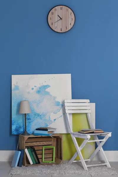 Diseño de la habitación con silla blanca, estantería, imágenes, lámpara y reloj sobre pared azul — Foto de Stock