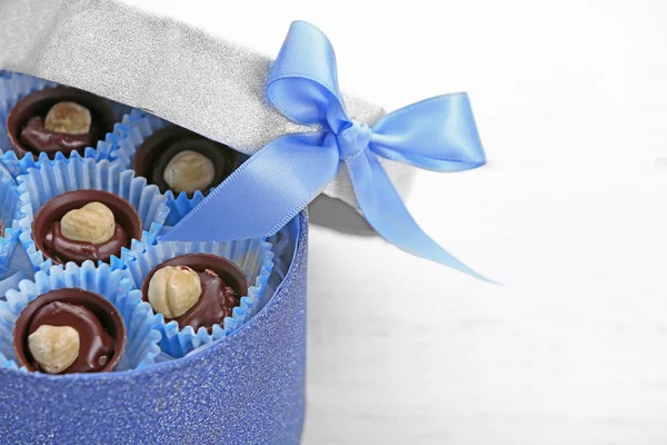 Schokoladenbonbons in einer Geschenkbox mit Schleife auf hellem Holzgrund, Nahaufnahme — Stockfoto