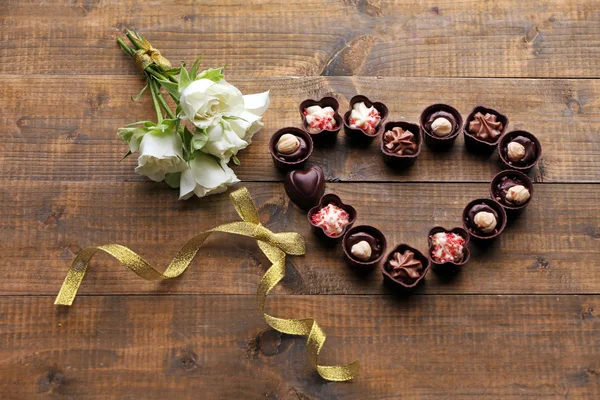 Conjunto de doces de chocolate formando coração em um fundo de madeira — Fotografia de Stock
