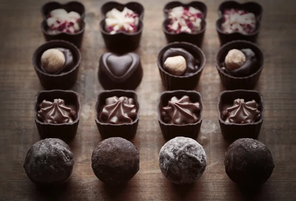 Conjunto de doces de chocolate em um fundo de madeira — Fotografia de Stock