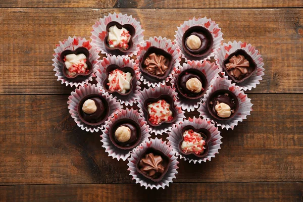 Uppsättning av choklad godis utgör hjärtat på en trä bakgrund — Stockfoto
