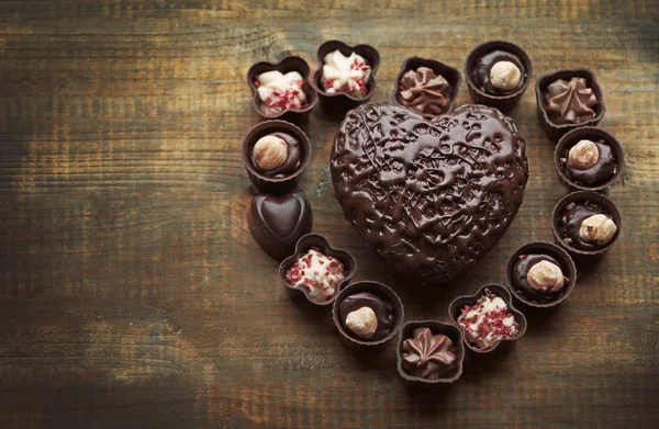 Set di caramelle al cioccolato che formano il cuore su uno sfondo di legno — Foto Stock