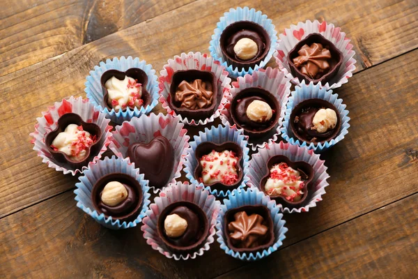 Sada čokoládové bonbony, které tvoří srdce na dřevěné pozadí — Stock fotografie
