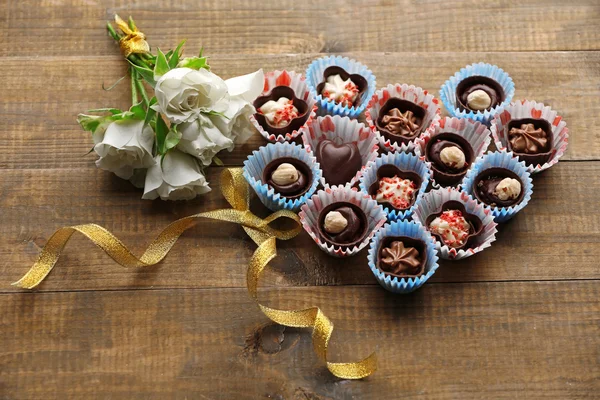 Conjunto de doces de chocolate formando coração em um fundo de madeira — Fotografia de Stock