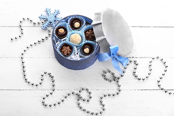 Čokoládové bonbony v dárkové krabičce s lukem na lehké dřevěné pozadí — Stock fotografie