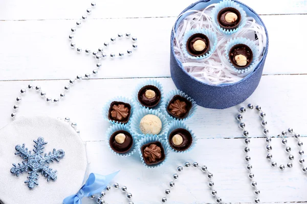 Chocolade snoepjes in een doos van de gift met een strik op een lichte houten achtergrond — Stockfoto