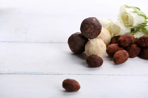 Conjunto de doces de chocolate com flores em um fundo de madeira leve — Fotografia de Stock