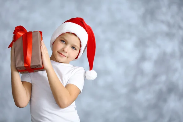 Jongen in kerstmuts met een geschenkdoos — Stockfoto