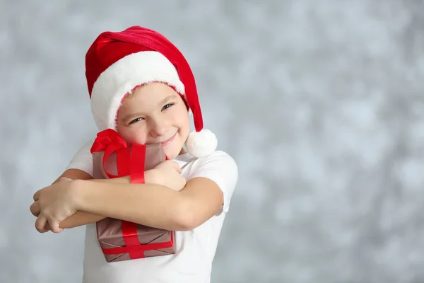 Junge im Weihnachtsmannhut mit Geschenkkarton — Stockfoto