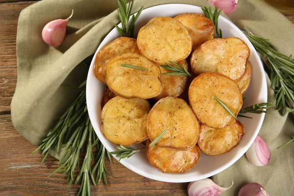 Läckra bakad potatis med rosmarin i skål på bordet på nära håll — Stockfoto