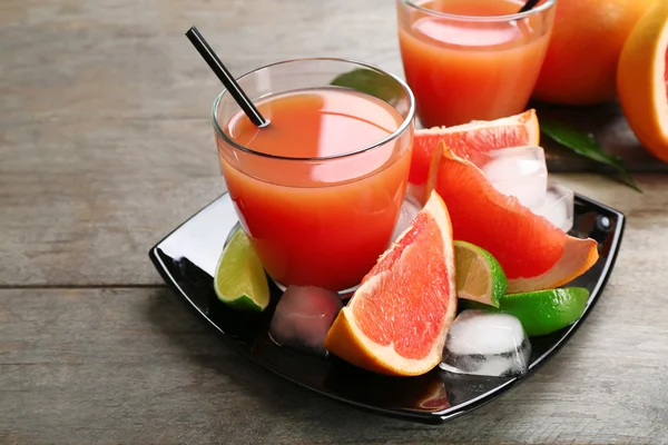 Citrus juice och färsk frukt på svart plåt — Stockfoto