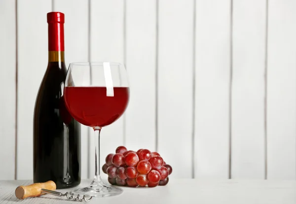 Κόκκινο κρασί με το σταφύλι σε φόντο ξύλινα τοίχων — Φωτογραφία Αρχείου