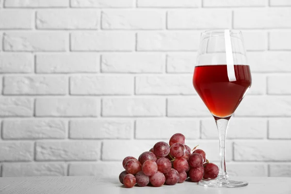 Vino tinto y uva sobre fondo de pared de ladrillo —  Fotos de Stock