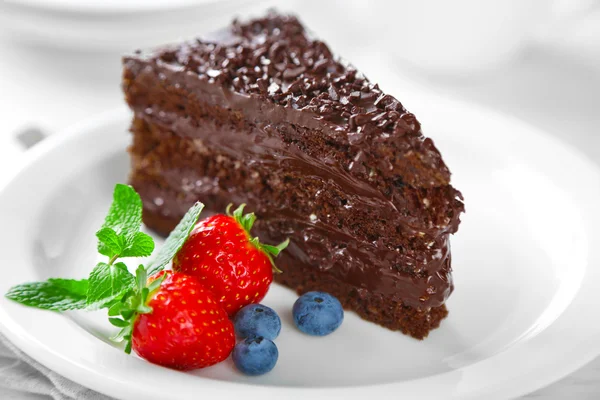 巧克力蛋糕，巧克力奶油和新鲜浆果在盘上，在明亮的背景上 — 图库照片