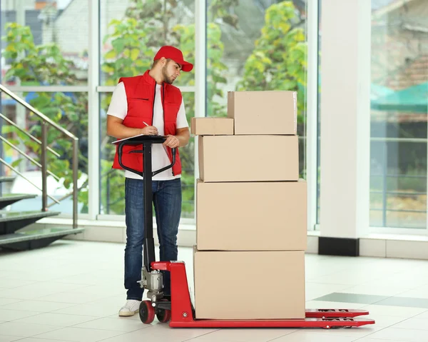 Cartero en uniforme rojo con paquetes en dolly — Foto de Stock