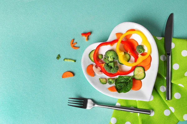 Корисні нарізані овочі на тарілці у вигляді серця на дерев'яному столі вид зверху — стокове фото