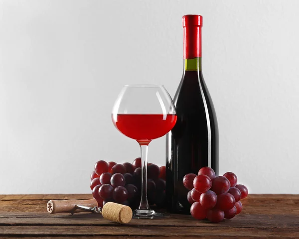 Wine and grape on wooden table against light background — Stock Photo, Image