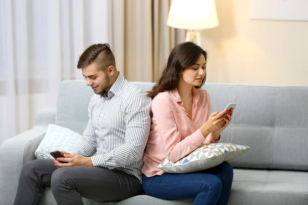 Casal com telefones celulares em casa — Fotografia de Stock