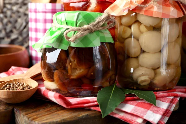 Jars with pickled vegetables and mushrooms on wooden background