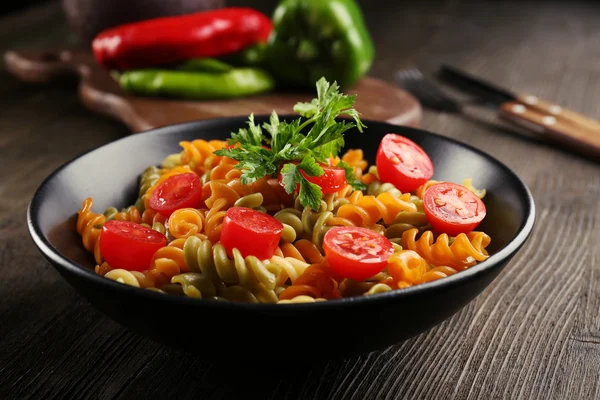 Delicioso plato de macarrones en tazón negro sobre mesa de madera servida — Foto de Stock