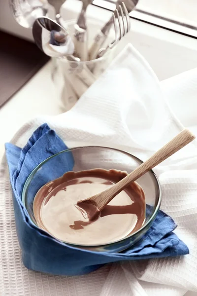 Melted chocolate in glass bowl, on wooden background — Stock Photo, Image