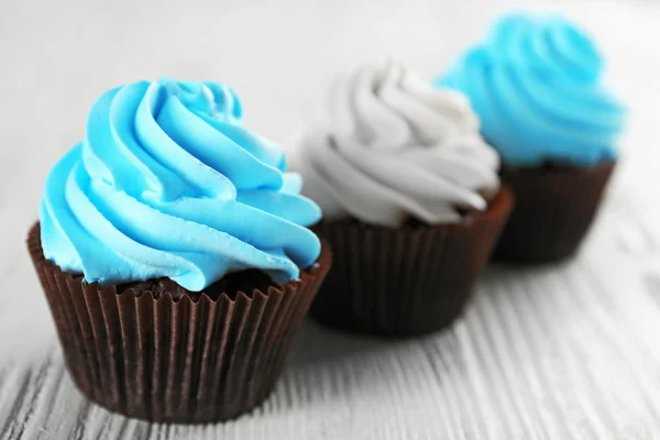 Verse heerlijke cupcakes in een rij op witte houten achtergrond — Stockfoto