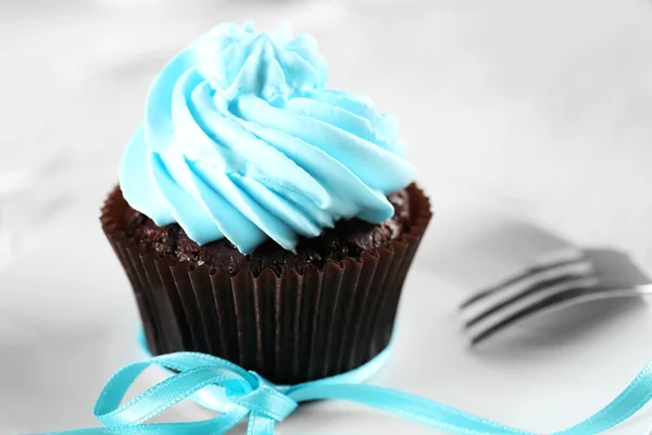 Läcker choklad cupcake med blå grädde på inredda träbord, närbild — Stockfoto