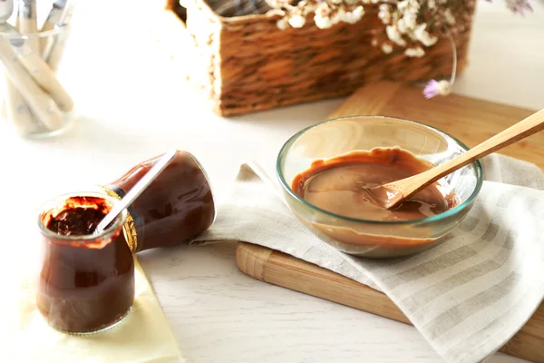 Chocolate derretido en cuenco de vidrio en bandeja, sobre fondo de madera —  Fotos de Stock