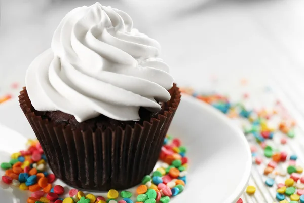 Delizioso cupcake al cioccolato decorato con dolciumi colorati sul tavolo servito, primo piano — Foto Stock