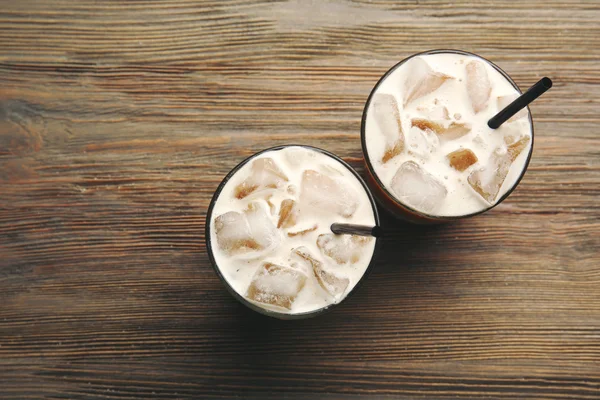 Duas xícaras de café gelado com palha em fundo de madeira — Fotografia de Stock