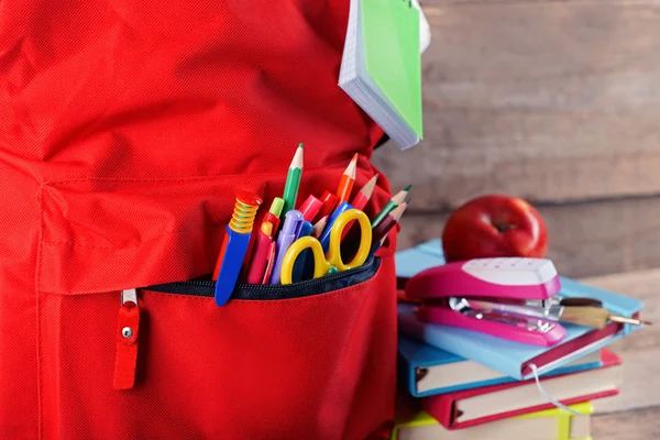 Červený batoh s knihami a jablko — Stock fotografie